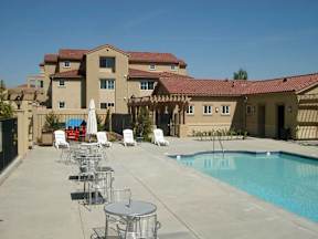 A pool area with chairs and umbrellas in front of a building.