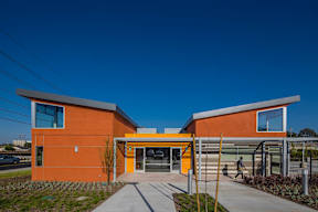 A modern building with orange walls and a yellow entrance.