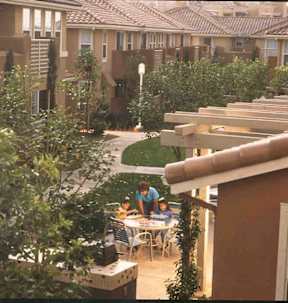 A family is sitting at a table outside a house.