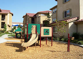 A playground with a slide and a sign with an 'X' on it.