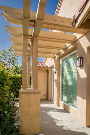 A long wooden pergola overhangs a patio.