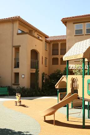 A playground with a slide and a yellow teddy bear.