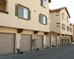 A row of houses with garages and green plants in front.