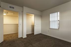 A room with a carpeted floor and a window with blinds.
