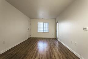 A room with wooden floors and a window with blinds.
