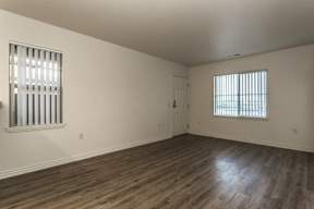 A room with wooden floors and a window with blinds.