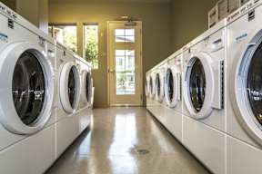 A row of white front load washing machines in a laundromat.