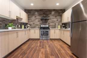 A kitchen with wooden floors and a stainless steel refrigerator.
