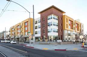 A street view of a multi-story building with a no parking sign.