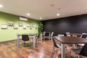 A room with tables and chairs and a green wall with words on it.