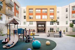 A playground with a slide, ball pit, and a person standing on a bench.