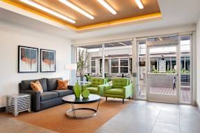 A living room with a black couch, green chairs, and a coffee table.