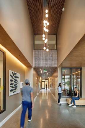A hallway with people walking and sitting on benches.
