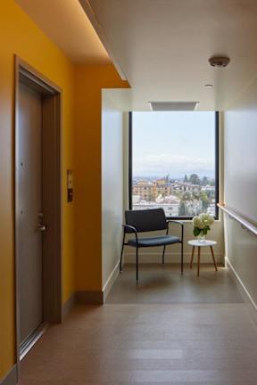 A hallway with a chair and a table with flowers on it.