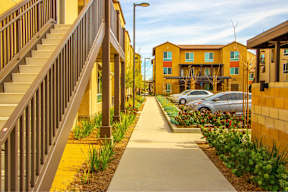 A long concrete walkway leads to a building with a staircase on the left.