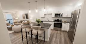 Bright and stylish kitchen at Contrast OTR in Cincinnati, Ohio, showcasing a spacious island, stainless steel appliances, white cabinetry, and modern pendant lighting
