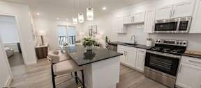 Open-concept living area at Contrast OTR in Cincinnati, Ohio, featuring a modern kitchen with sleek finishes, a cozy seating area, and large windows allowing for abundant natural light
