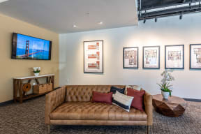San Rafael Apartments for Rent - Second and B Street - Top Floor Resident Lounge With a Couch, a TV, and Framed Pictures of the Apartments