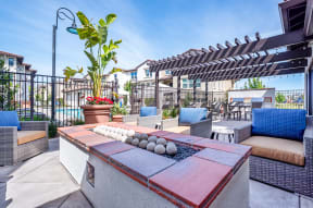 Three-Bedroom Apartments in Livermore, CA - Ageno - Raised Firepit with Wicker Chairs, Potted Plants, and Small White Circle Tables