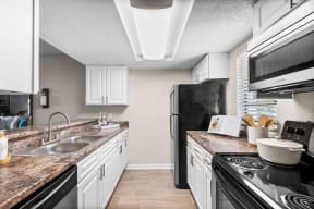 a kitchen with white cabinets and black appliances at The Bentley at Maitland, Florida, 32810