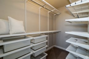 a walk in closet with white shelves and a pillow