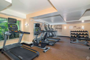 a room filled with lots of cardio equipment and a large window