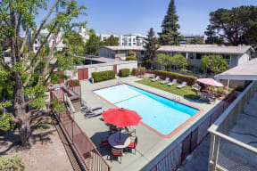 Apartments Near BART Station- Walnut Hill- Aerial View of Sparkling Pool with Sun-Lounge Chairs and Umbrella-Shaded Tables