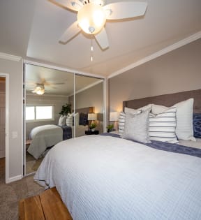 2-BR Apartments in Downtown Walnut Creek, CA- Walnut Creek- Bedroom with Large Plush Bed, Mirrored Sliding Door Closet, and Ceiling Fan