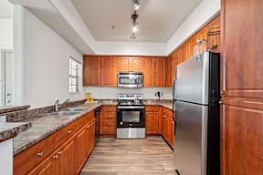 A kitchen with wooden cabinets and a stainless steel refrigerator.