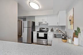 Colton, CA Apartments For Rent - Ardella At Reche Canyon - Renovated Kitchen With Granite Countertops, Stainless Steel Appliances, And White Cabinets.