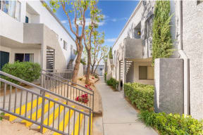 a pathway between two apartment buildings with a blue sky in the background