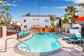 Dog-Friendly Apartments in Colton, CA- Ardella at Reche Canyon - Sparkling Pool Surrounded By Lounge Chairs and Views of the Apartment Homes