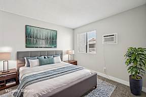 A bedroom with a bed, nightstands, and a plant.