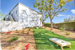 a backyard with a grassy area and a white house in the background