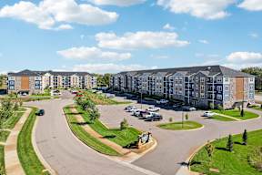 A large apartment complex with a parking lot in front.