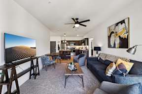 A living room with a grey couch and a painting on the wall.