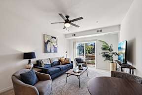 A living room with a blue couch and a ceiling fan.