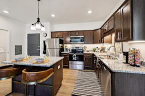 A modern kitchen with dark wood cabinets and stainless steel appliances.