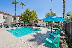 A pool surrounded by palm trees and sun loungers.