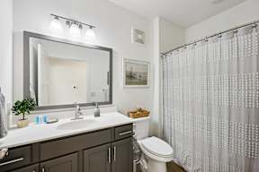 A bathroom with a white sink, toilet, and a shower curtain.