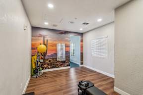 A room with a wall mural of a desert scene and a bench.