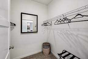 A white closet with a mirror and clothes hangers.