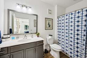 A bathroom with a white toilet, a sink with a mirror above it, and a shower curtain.