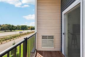 A balcony with a view of a highway and trees.