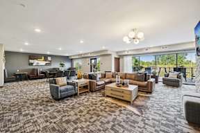A spacious living room with a variety of furniture and a view of the outdoors through large windows.