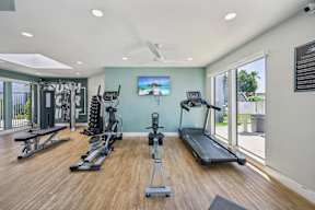 Glendale, AZ, Apartments for Rent - Ardella on 67th - Fitness Center with Wood-Plank Flooring and Expansive Windows, Equipped with a Treadmill, Elliptical Trainer, and a Rowing Machine.