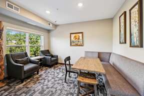 A living room with a grey couch, a wooden table, and a painting on the wall.