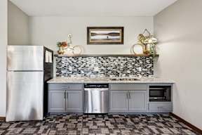 A kitchen with a stainless steel refrigerator and a tiled backsplash.