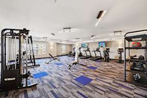 A gym with a variety of equipment including treadmills, weights, and exercise machines.