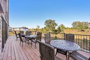 A balcony with a table and chairs overlooking a grassy area.